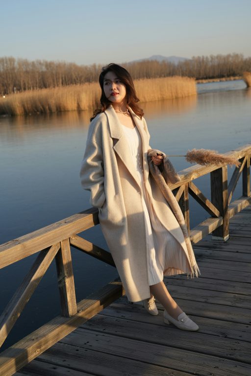 A petite woman wearing a maxi coat with helm just above the ankle.