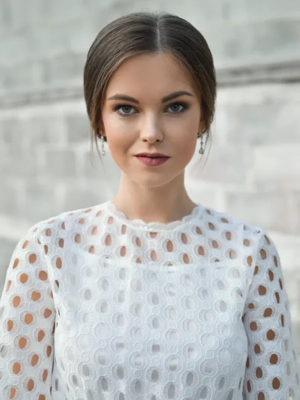 Petite model in a white lace top featuring intricate cutout patterns, styled with minimal makeup and a classic updo.