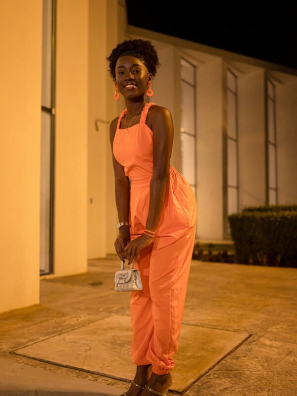 Petite woman wearing an orange jumpsuit with heels