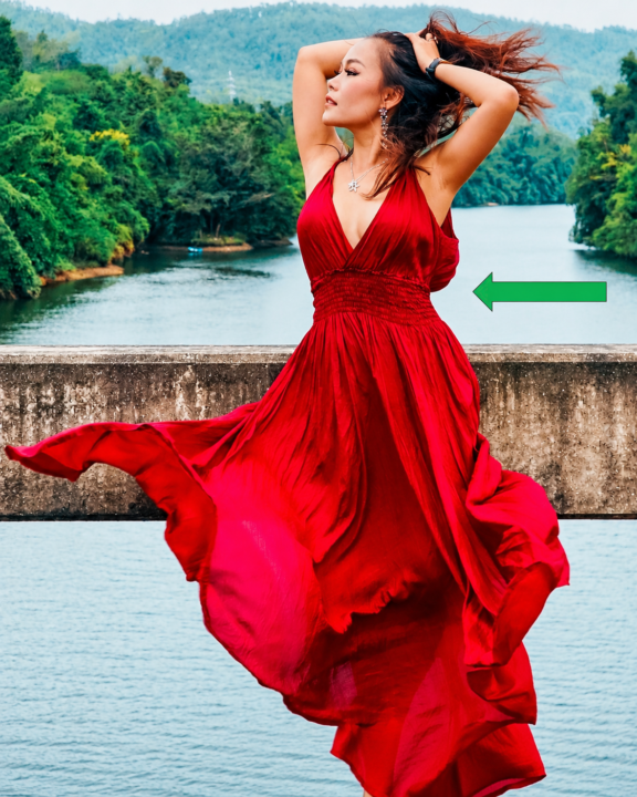 Woman wearing a flowing red maxi dress with a defined, elevated waistline highlighted by a green arrow, illustrating a flattering dress style for petite women.