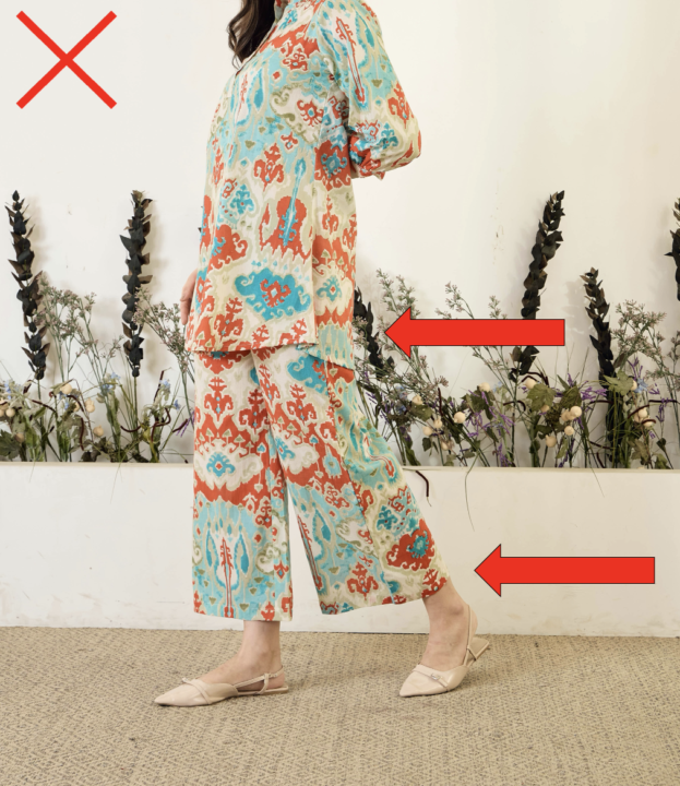 Woman wearing a long patterned top with a low hemline and wide-leg cropped pants ending high on the leg, illustrating proportions that can make petite legs look shorter.